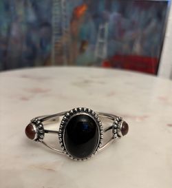 Southwest Style Sterling Silver Cuff Bracelet featuring a central oval black onyx stone and 2 brown jasper on sides. The design is characteristic of N