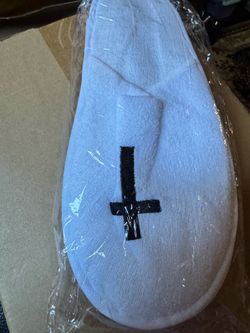 Soft white terry spa slippers. Black stitched cross detail on top. Cushioned slip-on design. Great for home or spa use. Fit size 9-10. 12 pair in box.