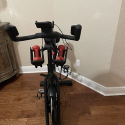 Schwinn IC4 or BowFlex C6 indoor stationary cycling bike featuring magnetic resistance and a pair of dumbbells. 