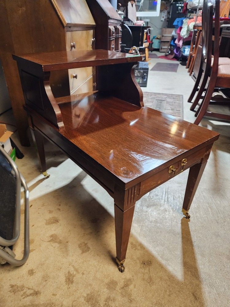 Mersman two level end table with brass feet and wheels.