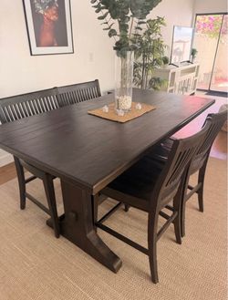rustic dark wood dining set featuring a solid trestle table paired with a matching bench and slat-back chairs.
