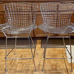 A pair of modern-style bar stools with chrome-plated wire