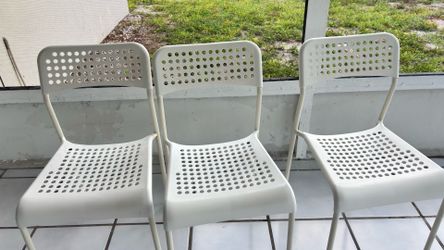 The KEA Adde chair has white steel legs with a perforated plastic seat and back surface.