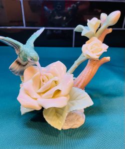 Beautiful vintage porcelain figurine of a hummingbird in flight over roses