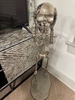 Metal skeleton holding head statue