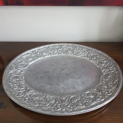 A large pewter serving tray with embossed floral and scrollwork decoration.