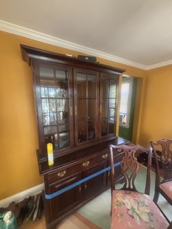 Dining room table with a full set of chairs in the China cabinet that is lit from the inside