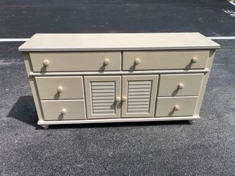 This off-white dresser features louvered cabinet doors and six smaller drawers