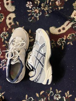 These ASICS GEL-1130 sneakers feature a white and navy blue colorway with silver accents.