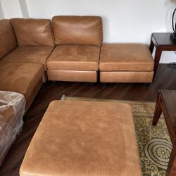 Brown suede sectional sofa, stone top dining table with four leather chairs, and modern wooden TV stand – all in great condition.