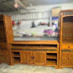 large rustic wood entertainment center with side towers 