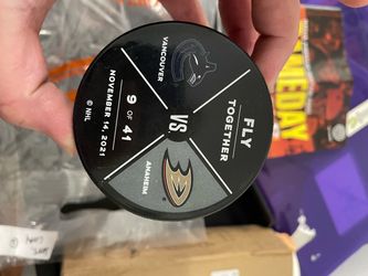 Warm up pucks, a hat, and game brochure for one of the pucks