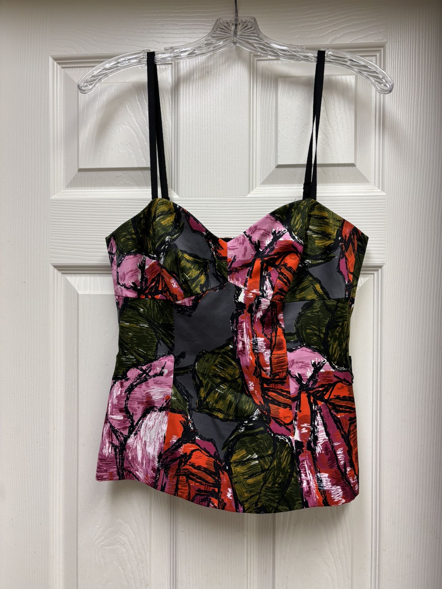 This elegant black corset top by Trina Turk features a bustier style with a structured bodice and fitted seaming details. The sleeveless design and ca
