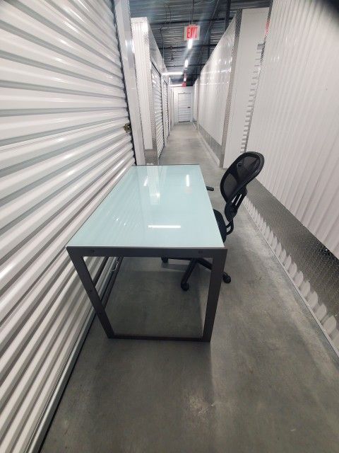 Frosted glass office desk with slide keyboard holder and office chair.