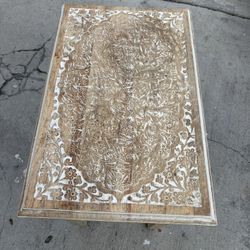 hand-carved wood side table with a white or distressed white finish applied to the legs 