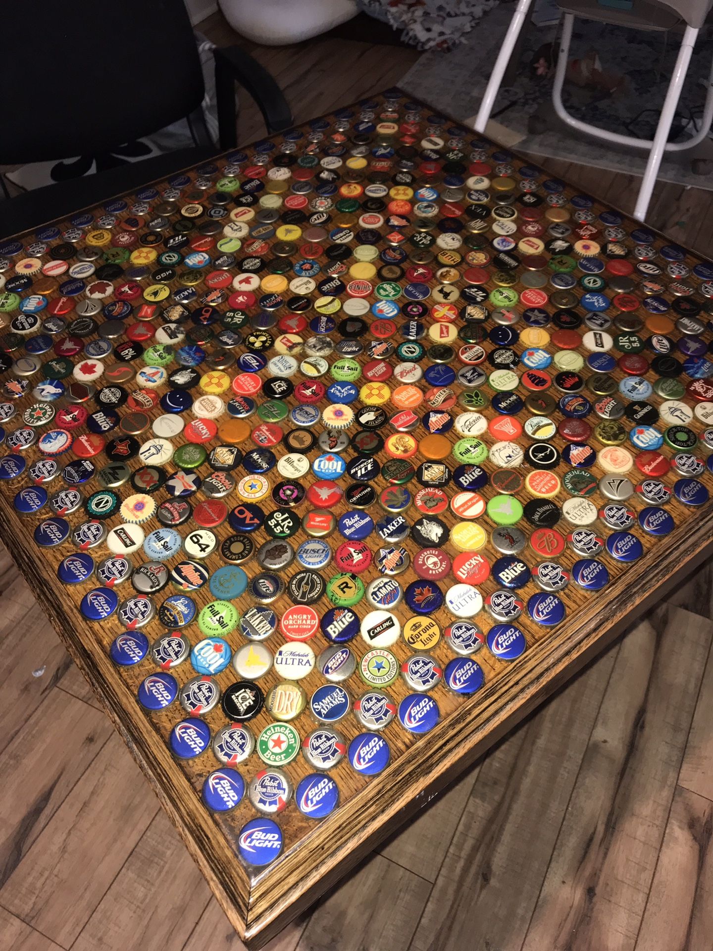 Wooden table with bottled beer caps under glass