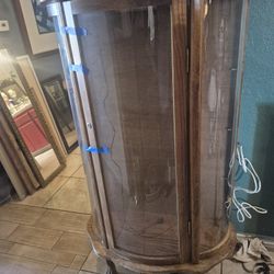 vintage oak curio cabinet featuring curved glass panels on the front and sides, supported by claw feet. 