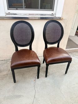 Two Brown leather chairs with black solid wood