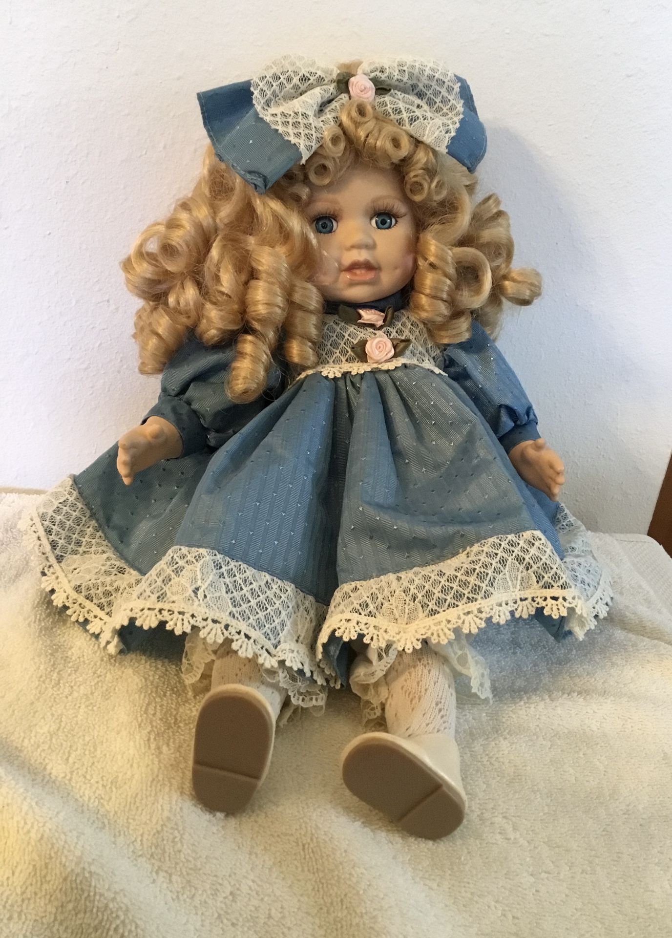 Curly blond haired blue eyed porcelain doll