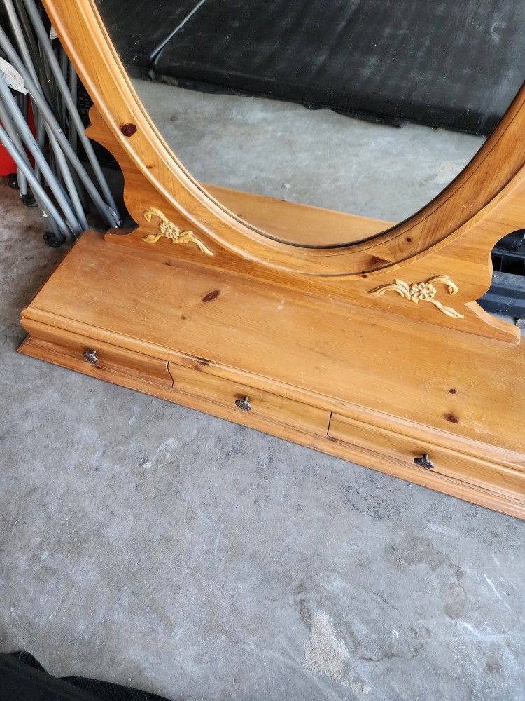 an oval, wood-framed dresser or vanity mirror
