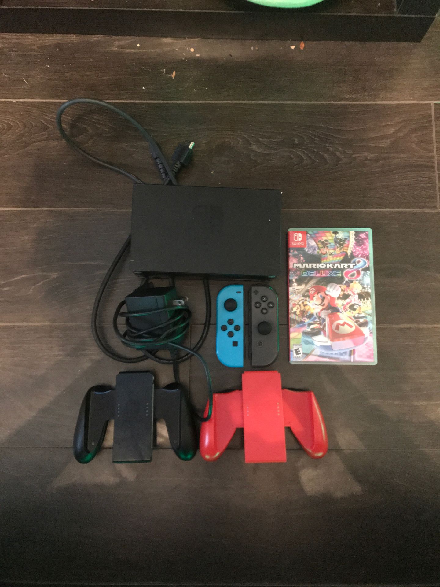 2 Switch Joycons, Mario Kart 8 Deluxe, a Switch Dock, 2 sets of grips, a Switch power plug, and