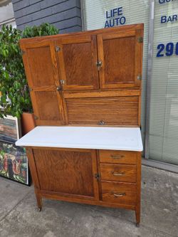 This piece of furniture is an antique oak Hoosier-style kitchen cabinet or cupboard.