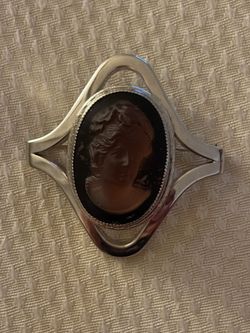vintage cameo brooch, which appears to be made from a glass or tiger's eye carved center set in a silver-toned metal fram