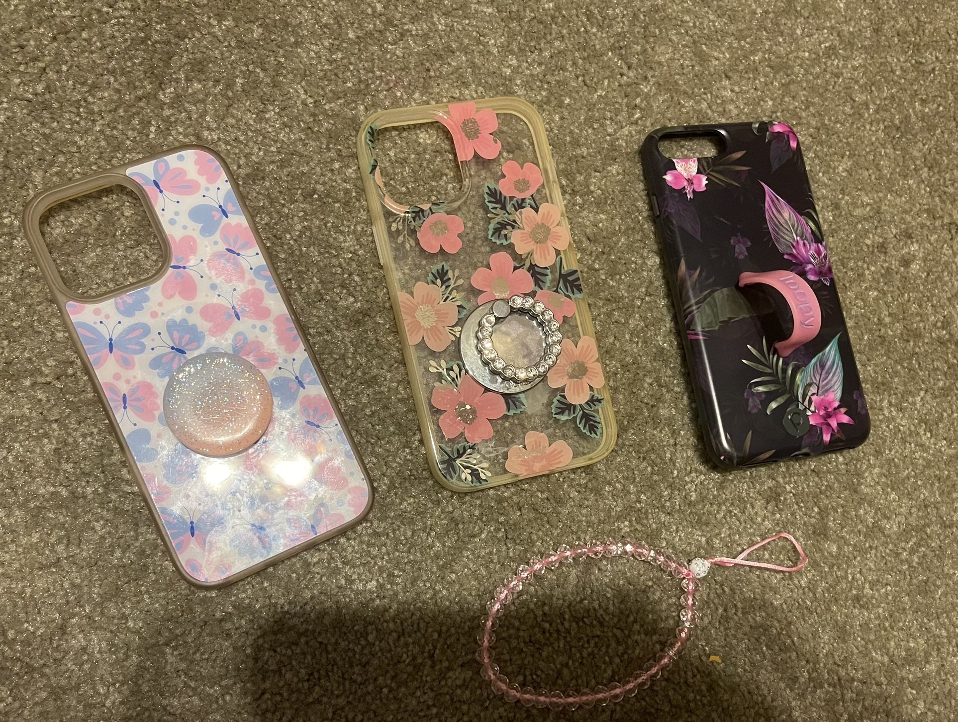 3 Different Phone Cases And A Phone Charm.