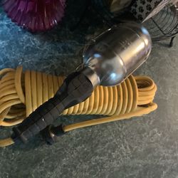 incandescent hand-held work light, commonly referred to as a trouble light or drop light, attached to a yellow extension cord.Features a protective me