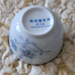 Porcelain teacup featuring a blue and white floral or cherry blossom design.