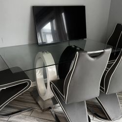 Modern glass dining table with sculptural base + chairs.
