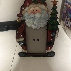 decorative holiday picture frame featuring a Santa Claus design holding a Christmas tree. 