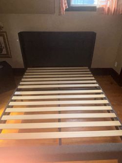Queen-size upholstered platform bed frame in dark gray, in good used condition.