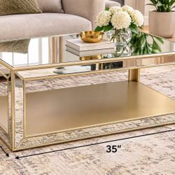 Mirrored Gold Coffee Table – 35” x 23” x 18”  Beautiful modern coffee table with a mirrored glass top and elegant gold-tone frame. Features a spacious