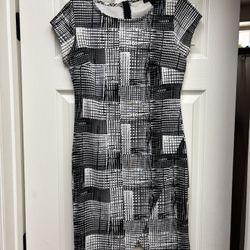 This elegant sheath dress by Attention features a striking black and white geometric pattern, perfect for work or cocktail occasions. With its cap sle