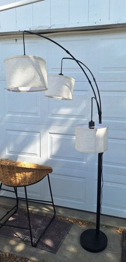 Modern 3-light arc floor lamp featuring hanging fabric drum shades and a sturdy black arched design