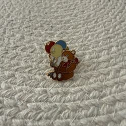 Vintage enamel pin of a teddy bear holding balloons.