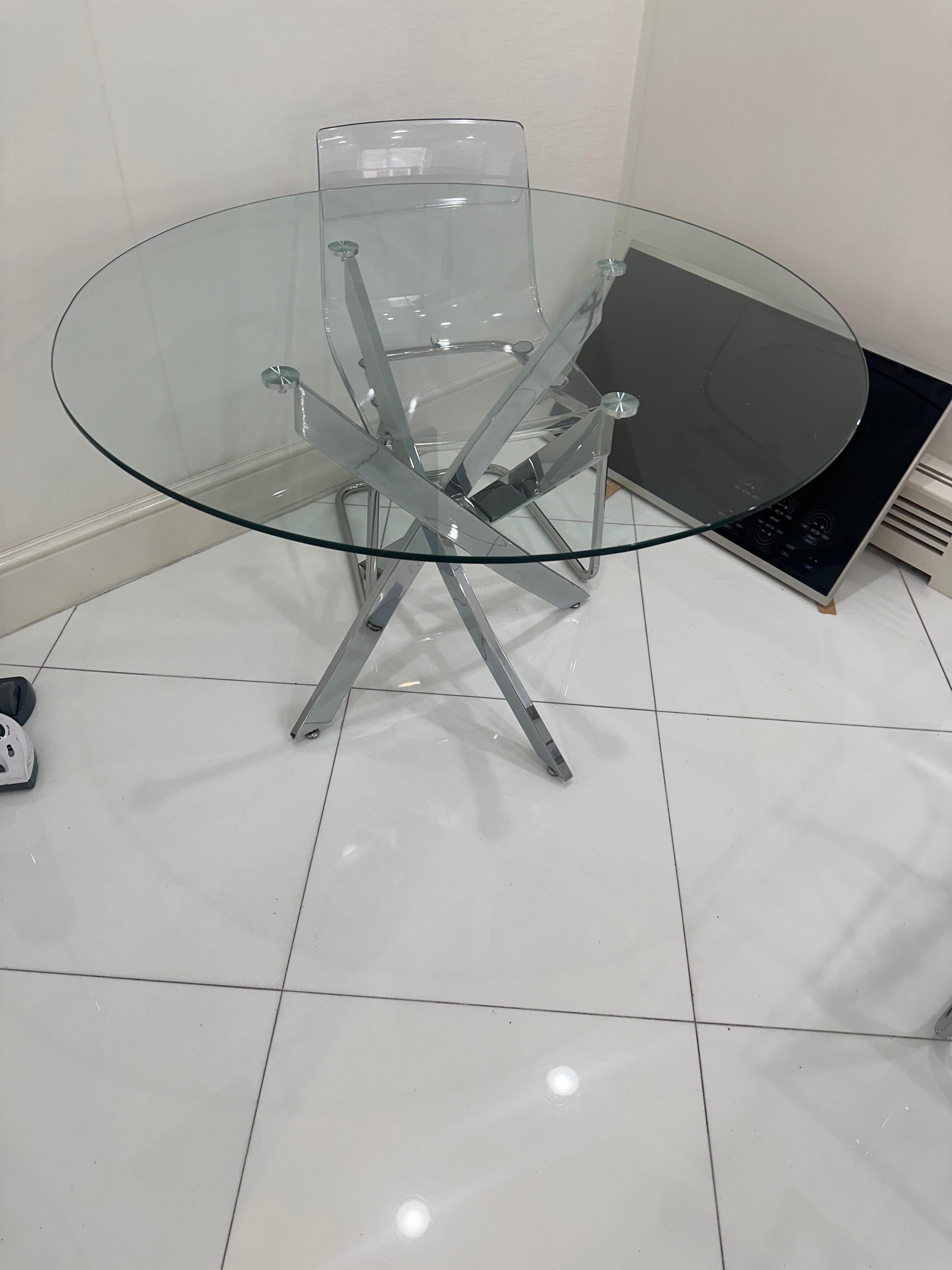 Modern round glass dining table with a chrome criss-cross base