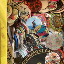 displays a collection of Pogs (also known as milk caps) and slammers within a yellow carrying case, which is identified as a World POG Federation Micr