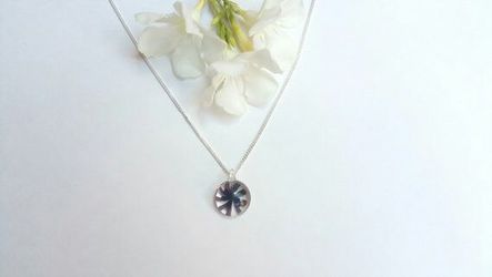 Necklace with handblown round glass pendant with painted purple flower on a silver colored chain
