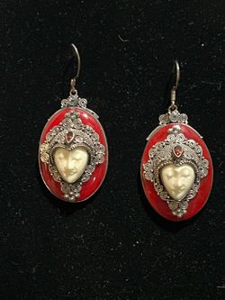 sterling silver dangle earrings featuring hand-carved bone faces surrounded by intricate red enamel and garnet accents, likely crafted in Bali