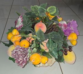 Large decorative artificial fruit‑flower centerpiece. Mixed faux peaches, apricots, grapes and colorful fabric flowers with green foliage. Comes in an