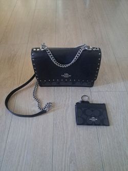 The Coach Klare Crossbody Bag in Black Studded Signature Chain is a stylish and edgy handbag designed for women by the renowned brand Coach. This cros