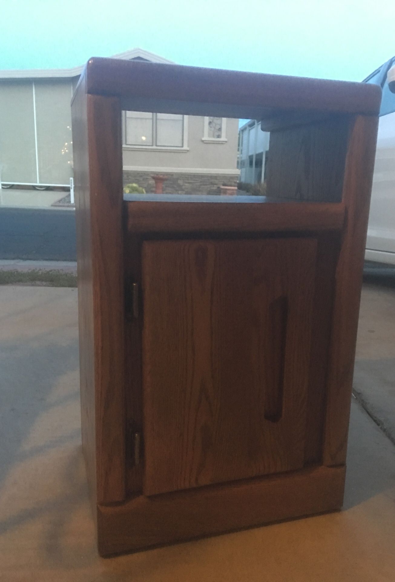 Small oak nightstand with shelf and cabinet.