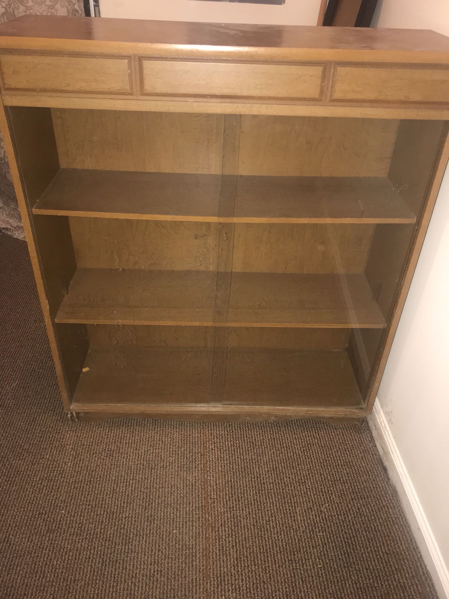 Wooden bookshelf with sliding glass doors.