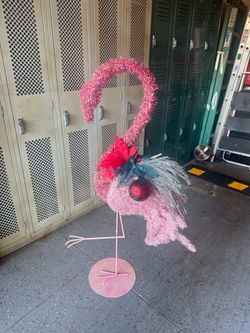 Vintage pink flamingo Christmas decoration, standing 49 inches tall! Features shimmering pink tinsel, a festive poinsettia, ornaments, and a matching