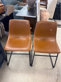 dining chair features tan leatherette upholstery and a matte black powder-coated steel base