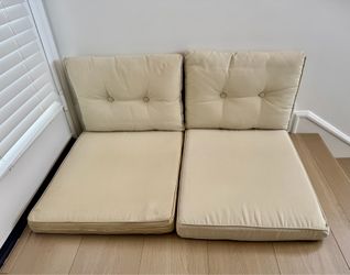 Two beige outdoor deep seat patio cushion sets.