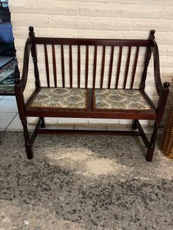 vintage spindle-back settee features a dark wood finish and floral upholstered seats