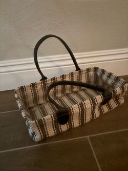 woven striped fabric basket with dark brown leather handles and trim.